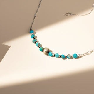 Necklace with turquoise and silver beads on a neutral background