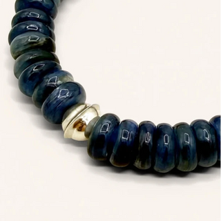 Blue beaded bracelet with a gold accent on a white background