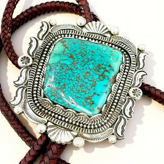 Silver pendant with a turquoise stone on a beige background