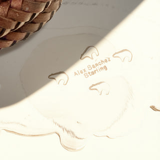 Silver stamp with 'Alex Sanchez Sterling' on a beige background