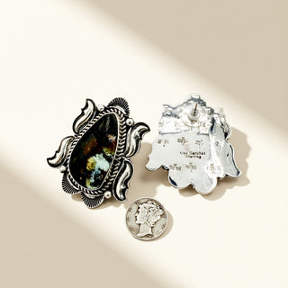 Silver earrings with black stone and coin on beige background 