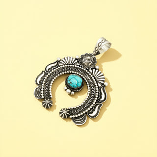 Silver pendant with turquoise stone on a beige background