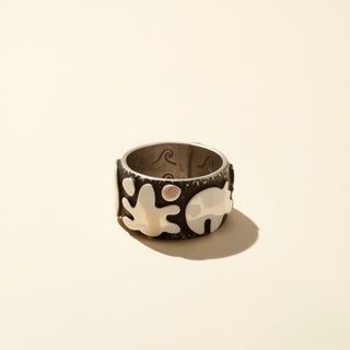 Silver ring with elephant design on a beige background