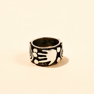 Black and silver ring with hand design on a beige background