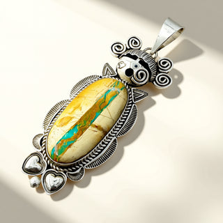 Silver pendant with a yellow and blue stone on a beige background