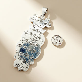 Silver pendant with wave design on a beige background