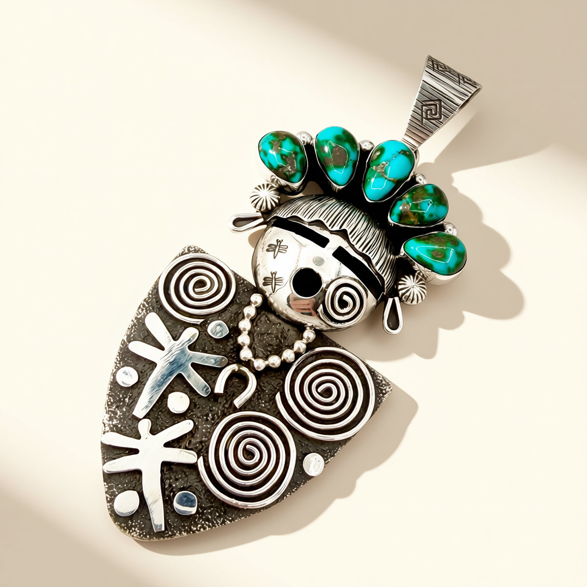 Native American-style silver and turquoise pendant on a beige background