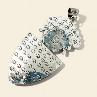 Silver pendants with wave patterns on a beige background