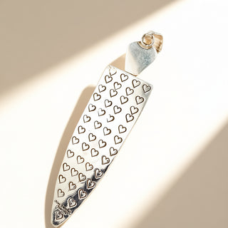 Silver pendant with heart patterns on a beige background