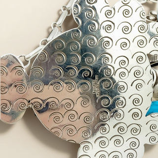 Metallic fish-shaped object with intricate patterns on a beige background