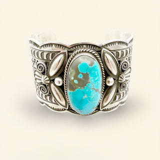 Silver cuff bracelet with a turquoise stone on a white background