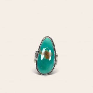 Turquoise ring with silver band on a beige background