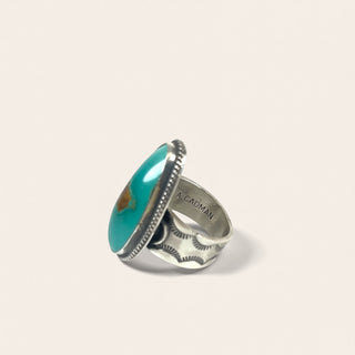 Silver ring with a turquoise stone on a light gray background