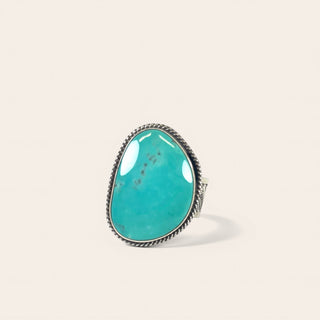 Turquoise ring with silver band on a beige background