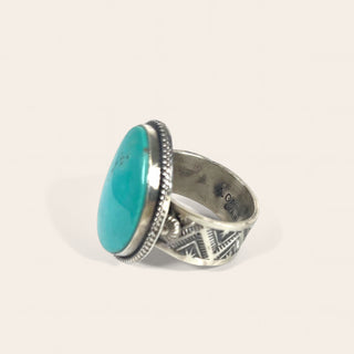 Silver ring with a turquoise stone on a light gray background