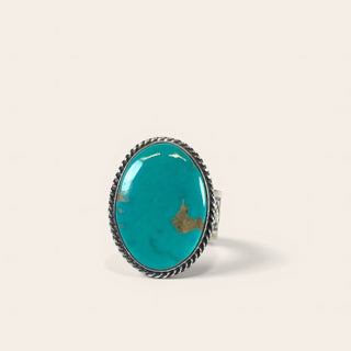 Turquoise ring with silver band on a beige background