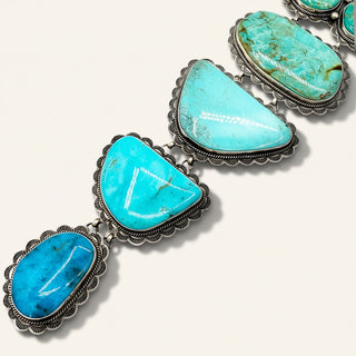 Turquoise stone necklace with silver setting on a white background