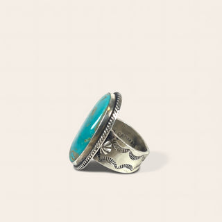 Silver ring with turquoise stone on a light beige background