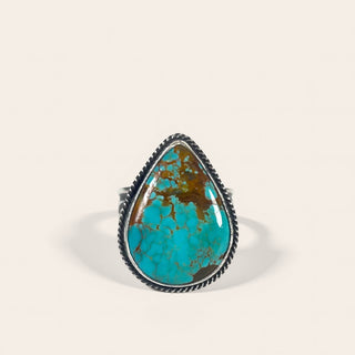 Turquoise ring with a teardrop-shaped stone on a beige background