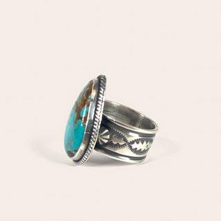 Silver ring with turquoise stone on a light beige background