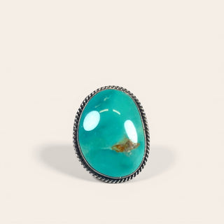 Turquoise ring with silver band on a beige background