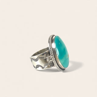 Silver ring with a turquoise stone on a light beige background
