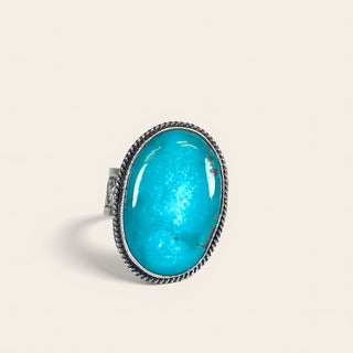 Turquoise ring with silver band on a beige background