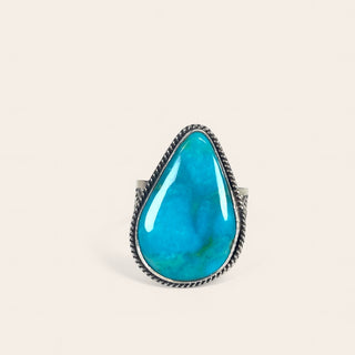 Turquoise ring with silver band on a beige background