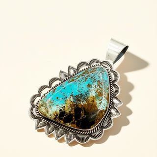 Silver pendant with turquoise stone on a beige background