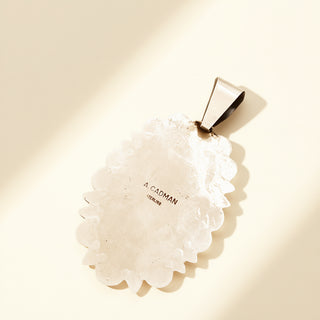 Silver pendant with stamp on a beige background