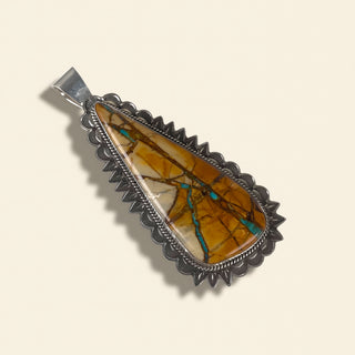 Jewelry pendant with amber and turquoise stone on a beige background
