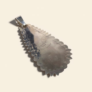 Decorative silver pendant on a beige background