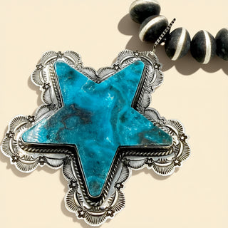 Silver star pendant with turquoise stone on a beige background