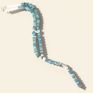 Necklace with blue beads and a white clasp on a beige background