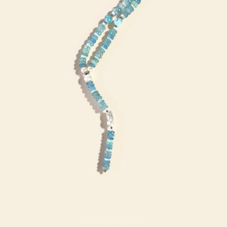 Beaded necklace with blue and silver beads on a beige background