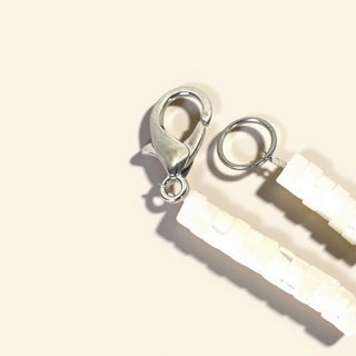 Close-up of silver earring components on a light beige background