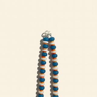 Beaded bracelet with blue, orange, and white beads on a beige background