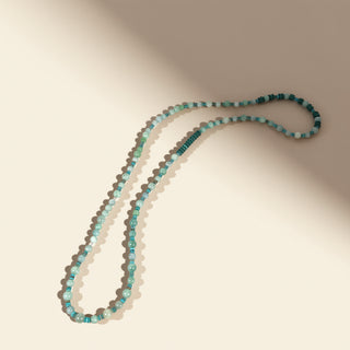 Beaded necklace with blue and green beads on a beige background
