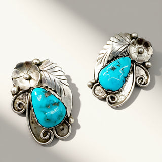 Pair of silver earrings with turquoise stones on a light background