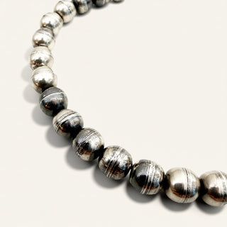 Close-up of a beaded bracelet with silver and gray beads on a white background