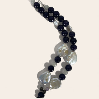 Necklace with black and white beads on a light pink background