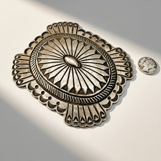 Decorative metal belt buckle with intricate design on a light background