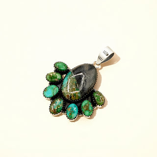 Jewelry pendant with green stones and silver accents on a white background
