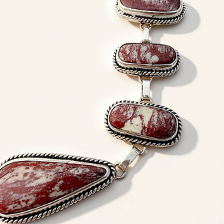 Silver necklace with red and white stone beads on a white background