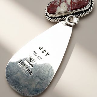 Silver pendant with engraved text on a beige background