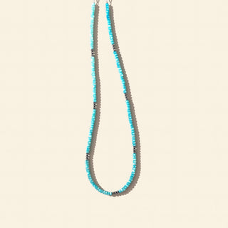 Necklace with blue and gray beads on a beige background