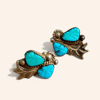 Pair of earrings with turquoise stones and gold accents on a white background