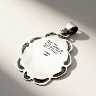 Silver pendant with engraved text on a light gray background
