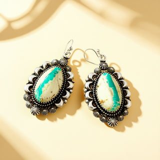 Pair of earrings with turquoise stones on a beige background