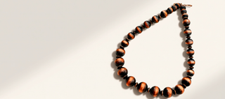 Necklace with black and orange beads on a light gray background